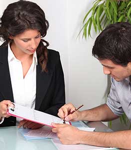 Image of a woman helping a man fill out a form