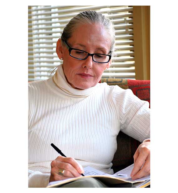 Woman wearing glasses, writing on a notebook